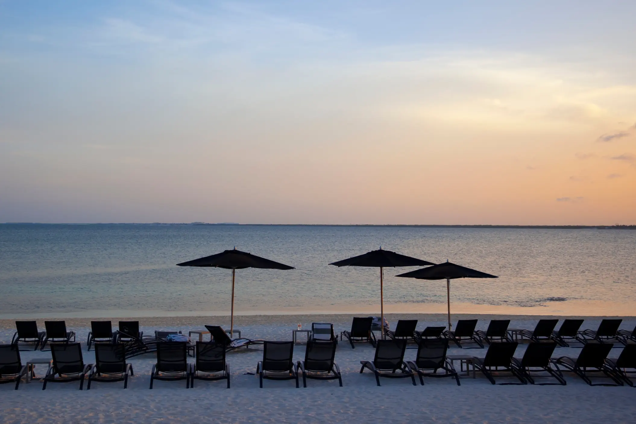 Lounge chairs and umbrellas on the sand at Nizuc Resort, Cancun at sunset