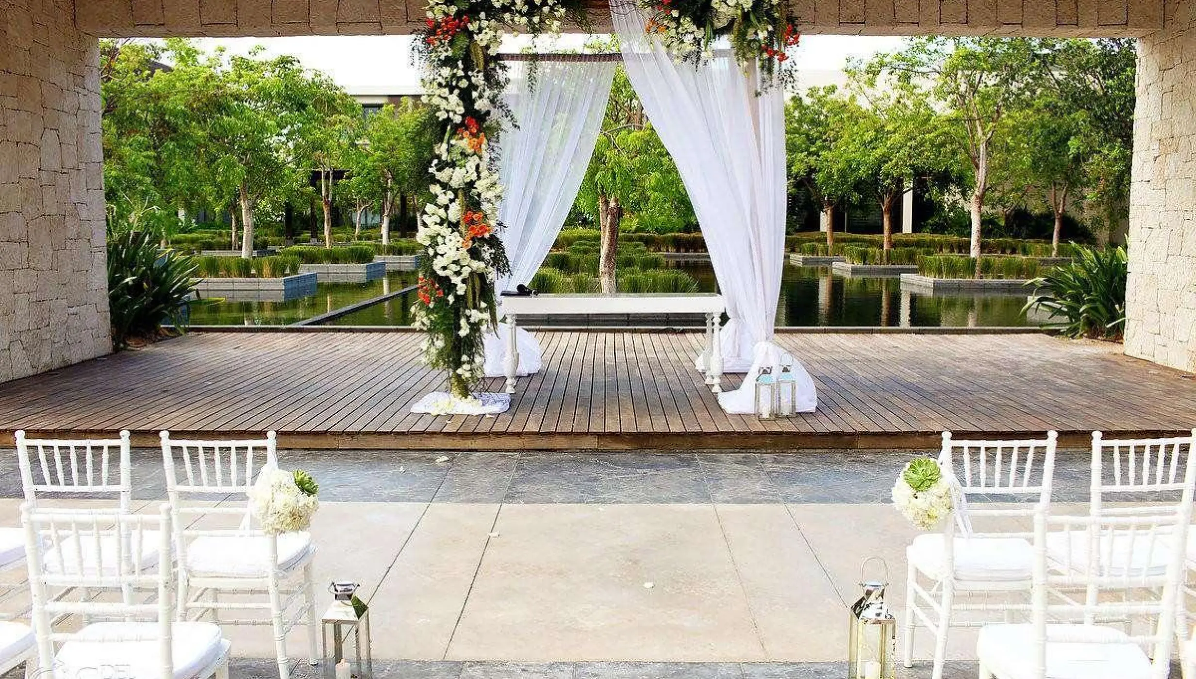 Akan Terrace wedding ceremony setup with white chairs and floral arch at Nizuc Resort, Cancun