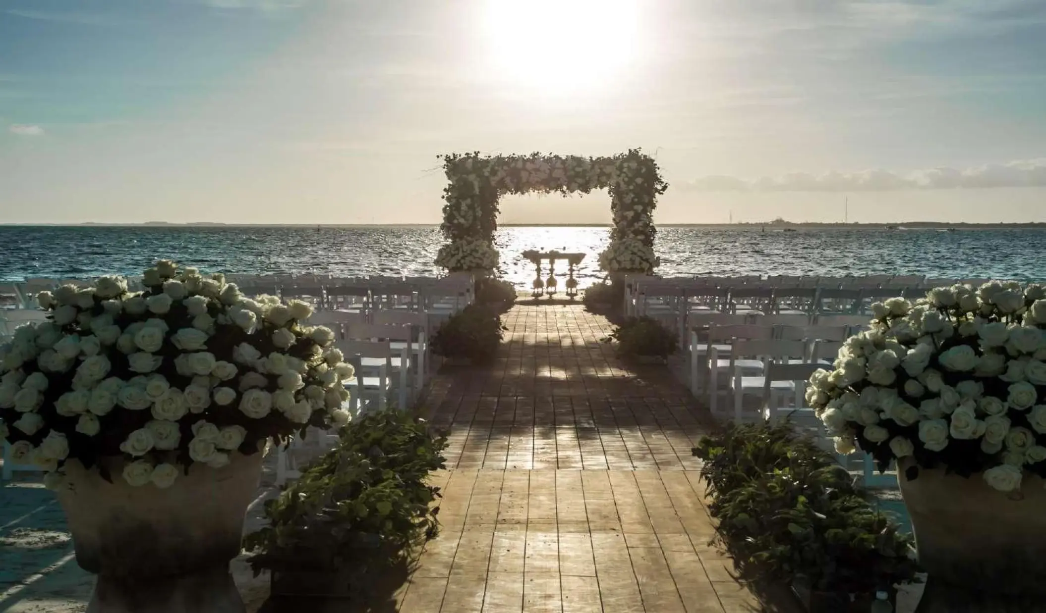 Beachfront wedding ceremony with floral arch at sunset, Nizuc Resort, Cancun