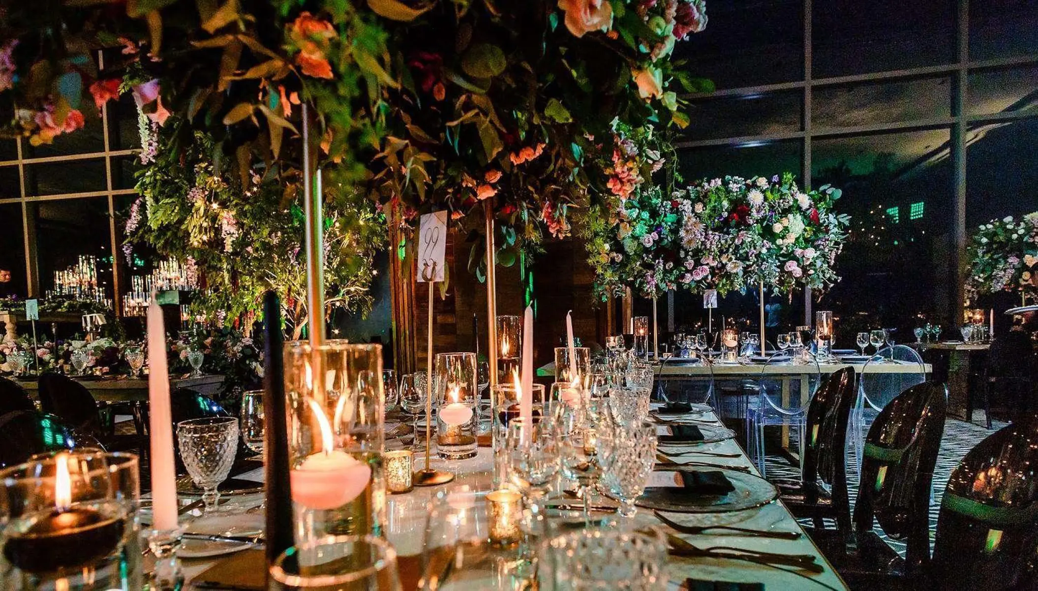 Indoor wedding reception with candles and tall floral centerpieces at Nizuc Resort, Cancun