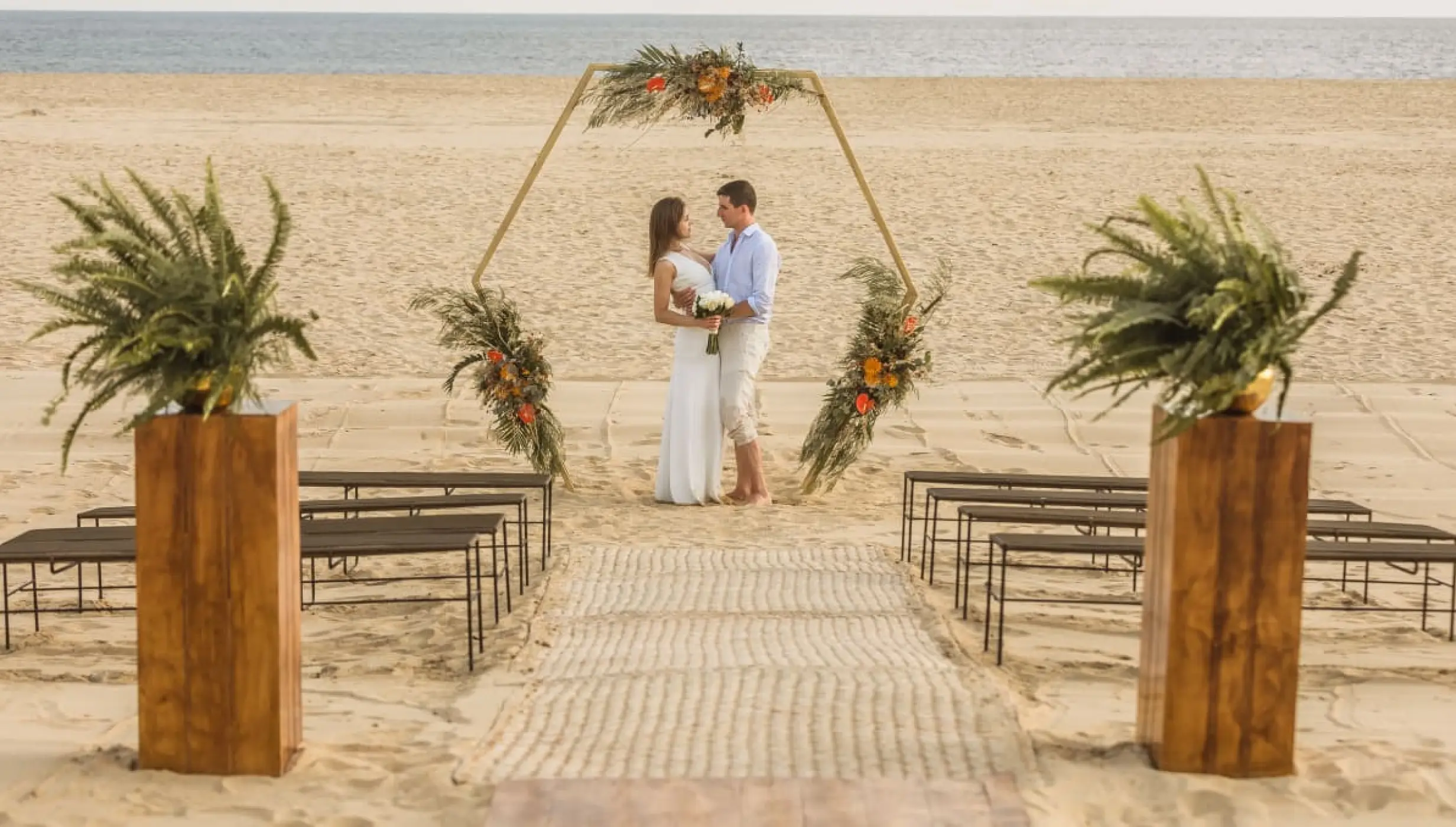Beach wedding ceremony with a hexagonal arch and couple at Nobu Hotel Los Cabos, Cabo San Lucas