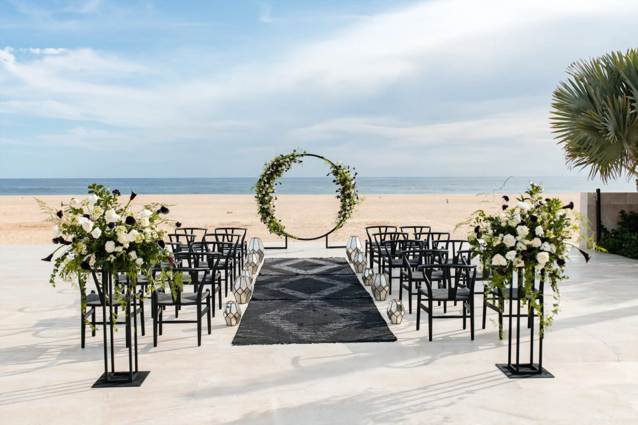 Terrace wedding ceremony with circular arch and black chairs at Nobu Los Cabos, Cabo San Lucas