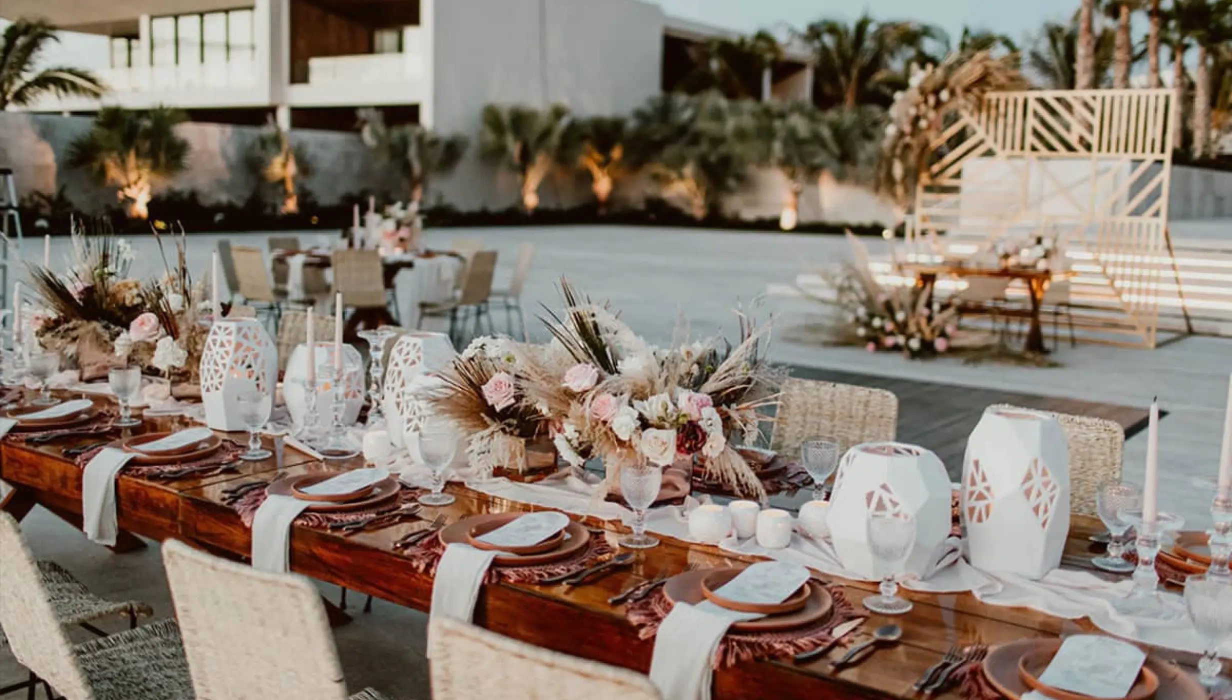 Long wooden wedding reception table with floral centerpieces and geometric lanterns at Nobu Hotel, Cabo San Lucas