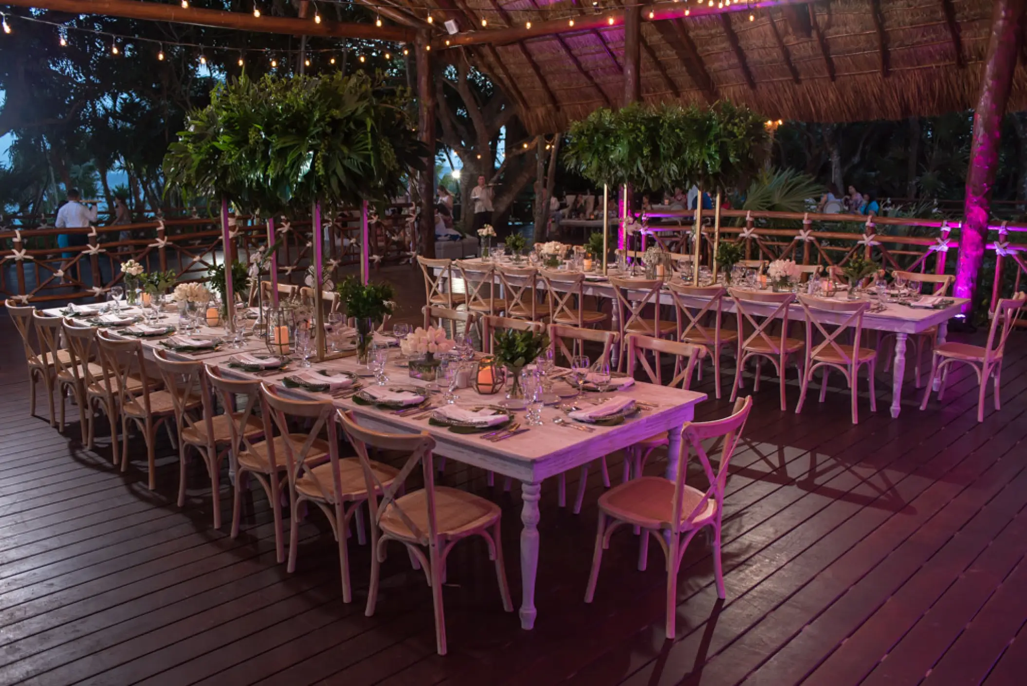 Wedding reception with long white tables and tropical greenery centerpieces at Occidental at Xcaret, Playa Del Carmen