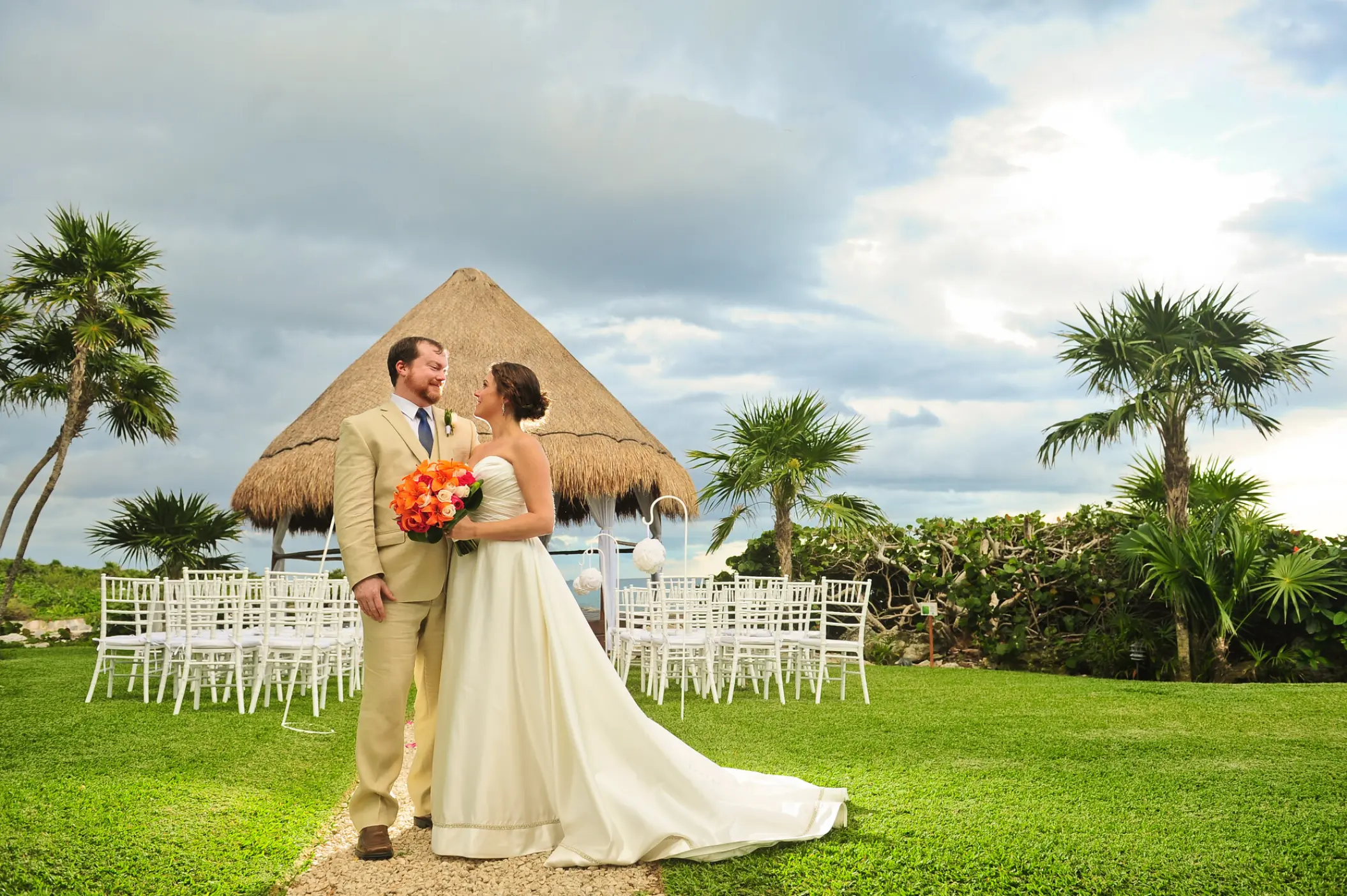 The bride and groom standing before a palapa wedding ceremony venue at Occidental at Xcaret, Playa Del Carmen