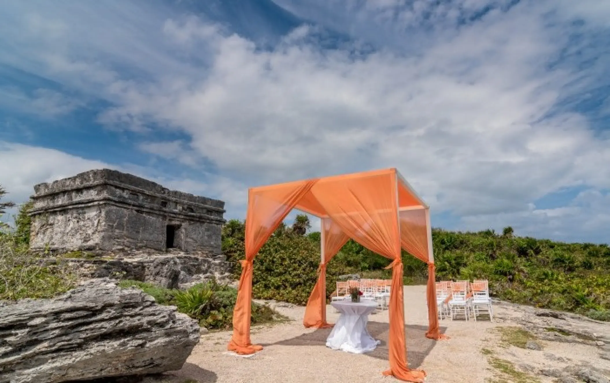 Orange huppah for a wedding ceremony by Mayan ruins at Occidental at Xcaret, Playa Del Carmen