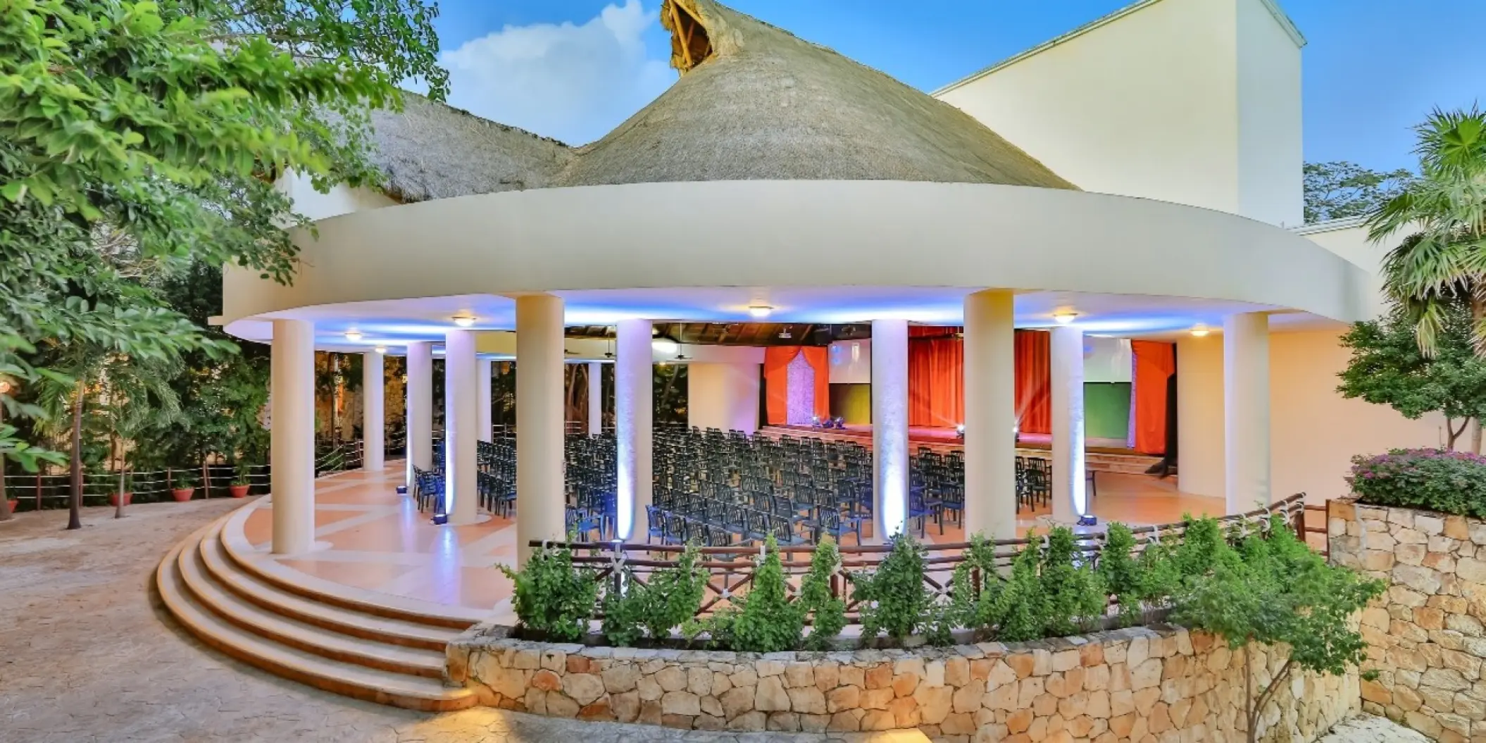 Circular outdoor theater under a thatched roof with blue lighting at Occidental at Xcaret, Playa Del Carmen