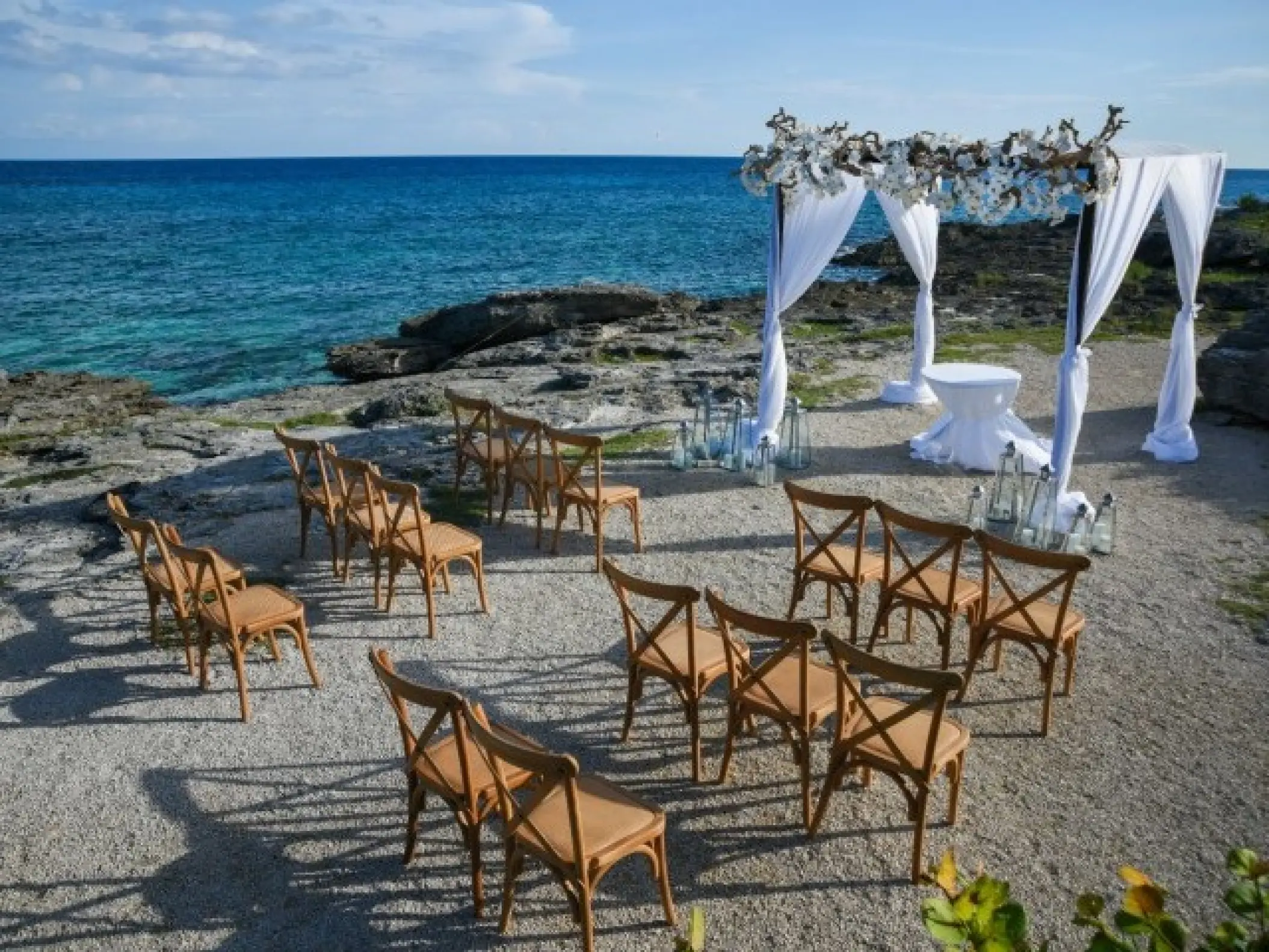 Oceanfront wedding ceremony setup with a white gazebo and wooden chairs at Occidental at Xcaret, Playa Del Carmen