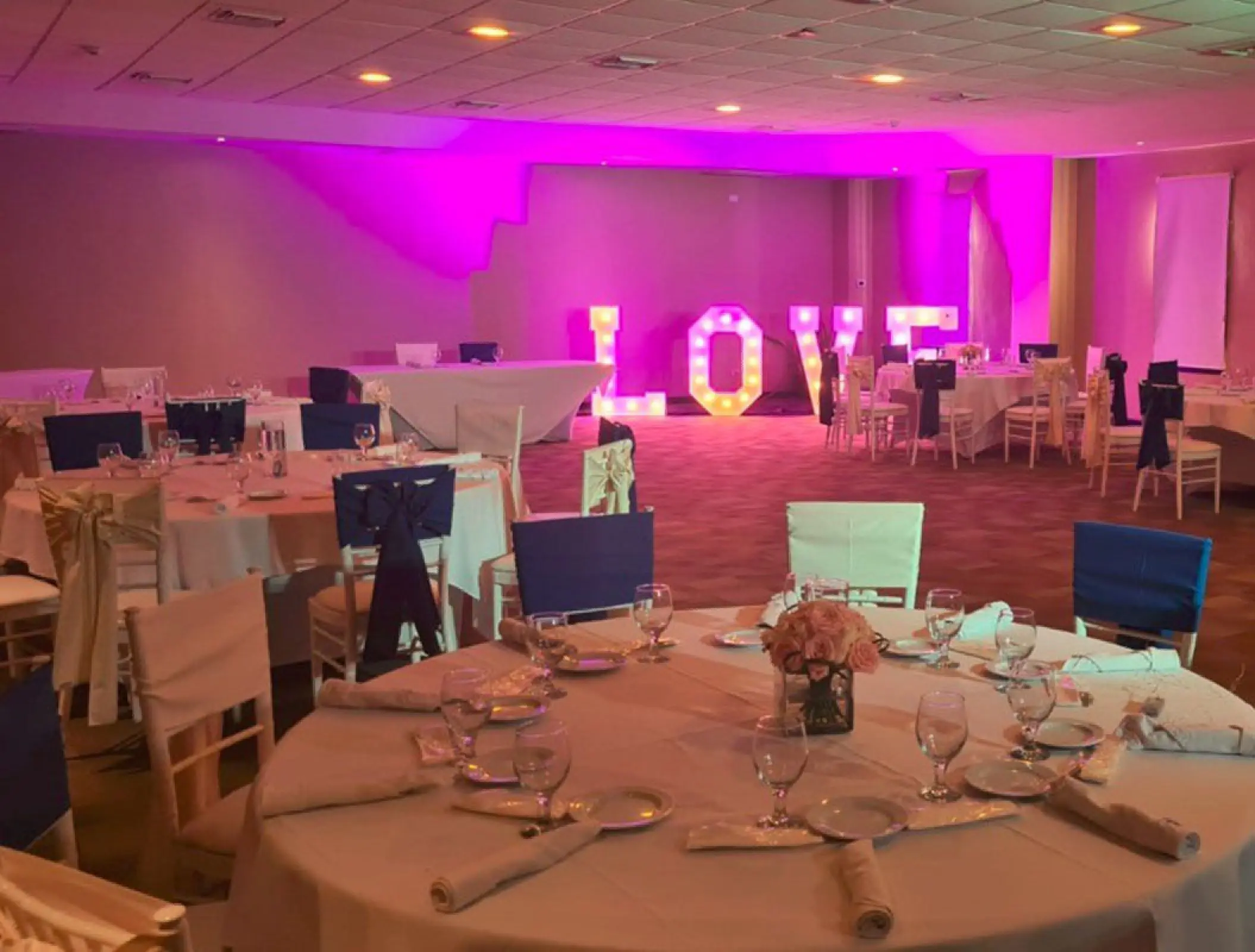 Ballroom wedding reception setup with purple uplighting and a lighted LOVE sign at Ocean Coral & Turquesa, Riviera Maya
