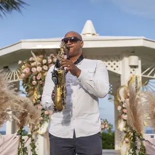 A saxophonist performing at an outdoor wedding ceremony at Ocean Coral & Turquesa, Riviera Maya