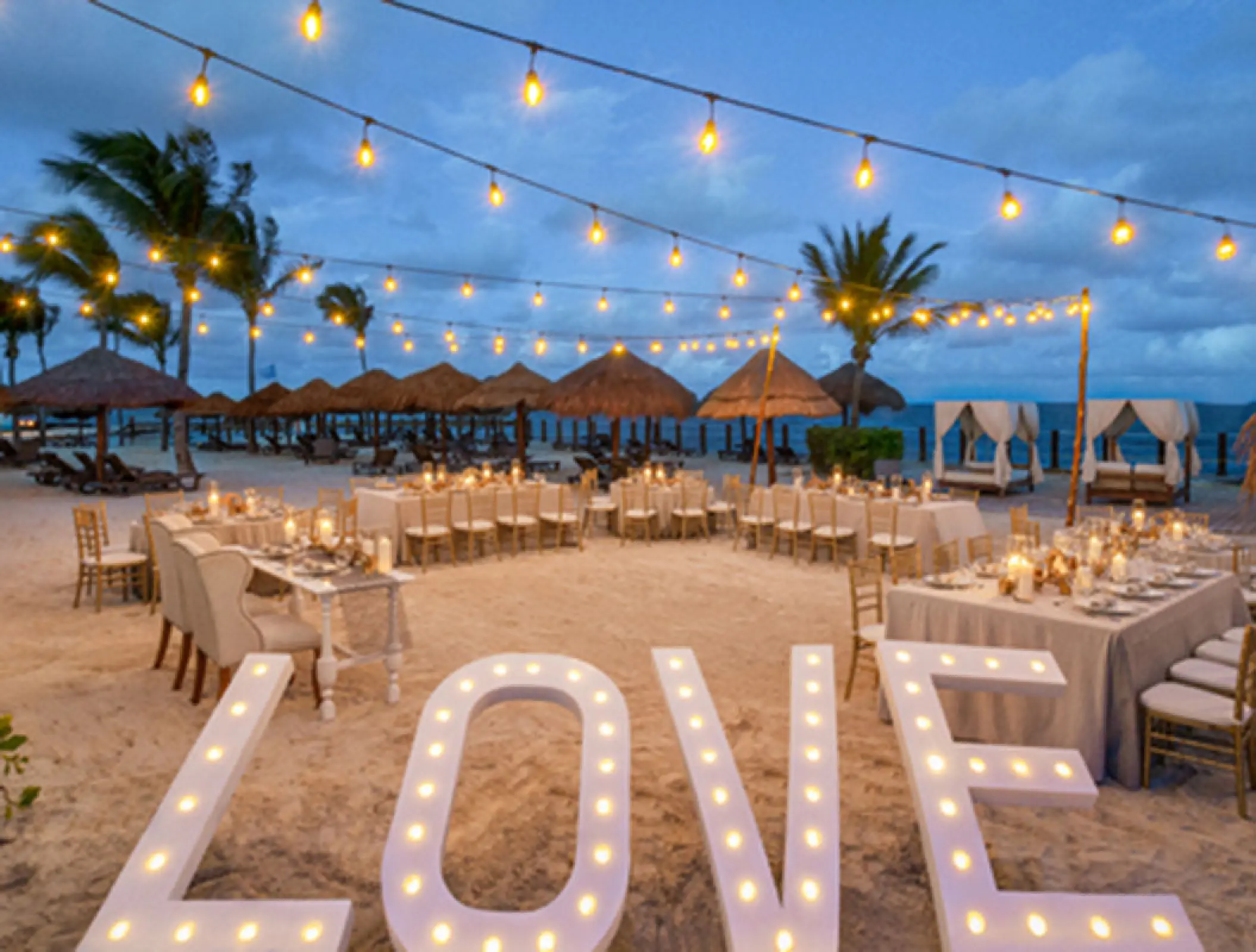 Beachfront wedding reception under string lights with LOVE marquee letters at Ocean Coral & Turquesa, Riviera Maya
