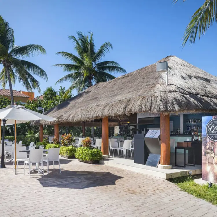 Thatched roof poolside bar and outdoor dining terrace at Ocean Coral & Turquesa, Riviera Maya