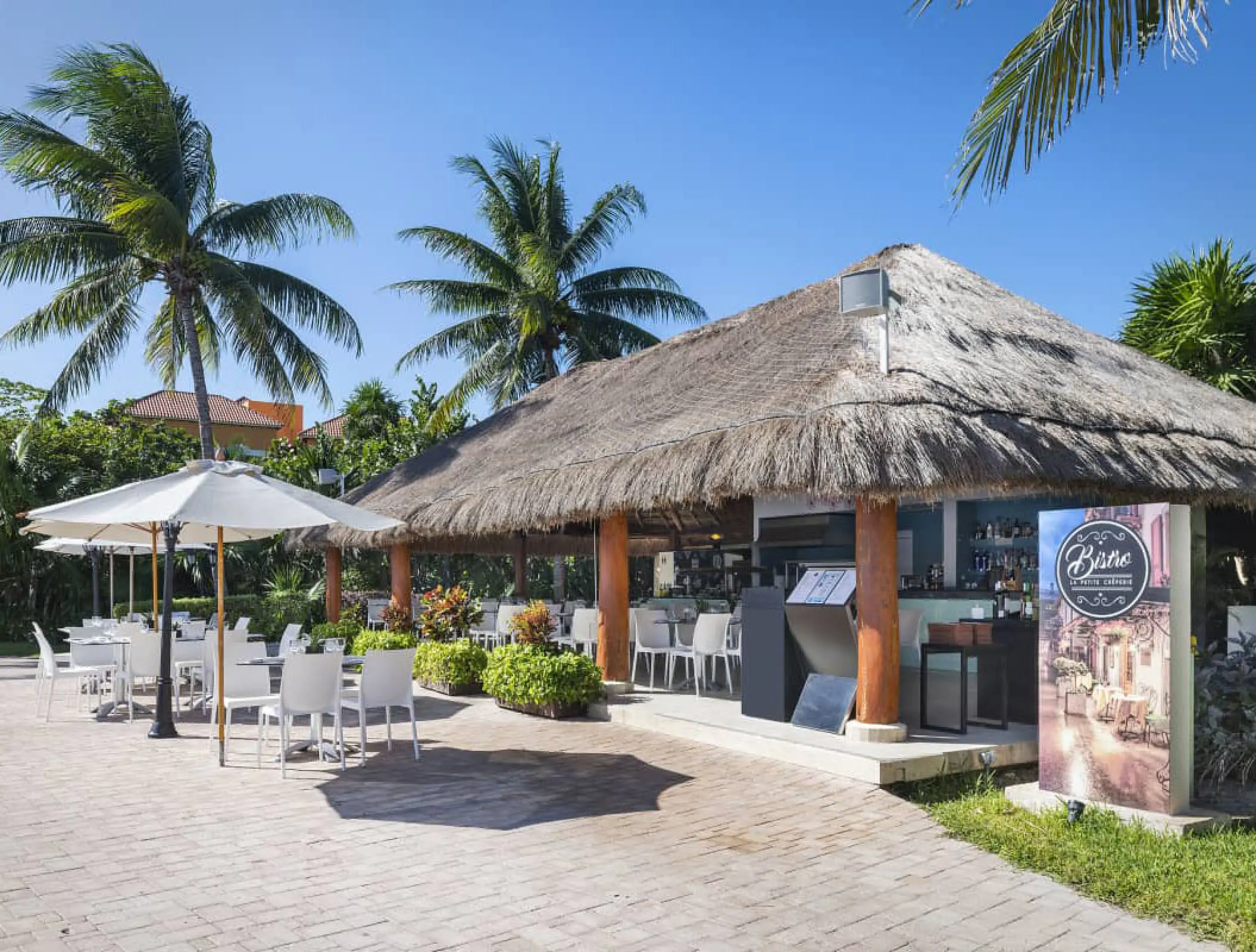 Thatched roof poolside bar and outdoor dining terrace at Ocean Coral & Turquesa, Riviera Maya