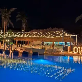 Evening wedding reception terrace with string lights and LOVE marquee sign at Ocean Coral & Turquesa, Riviera Maya