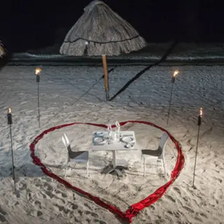 Private beach dinner for two with a heart-shaped red ribbon and torches at H10 Ocean Coral & Turquesa, Riviera Maya