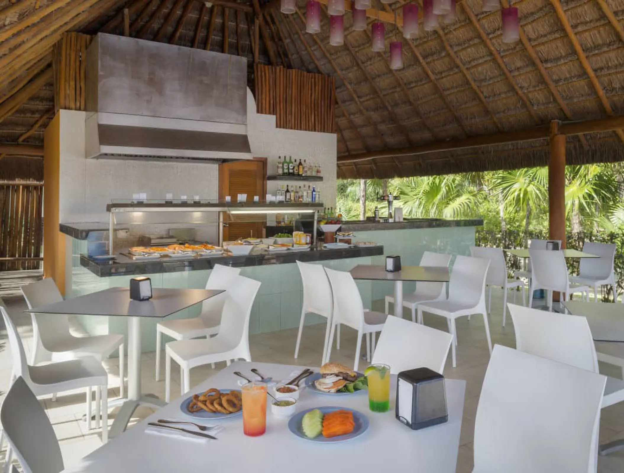 Outdoor snack bar with palapa roof and white seating at Ocean Coral & Turquesa, Riviera Maya