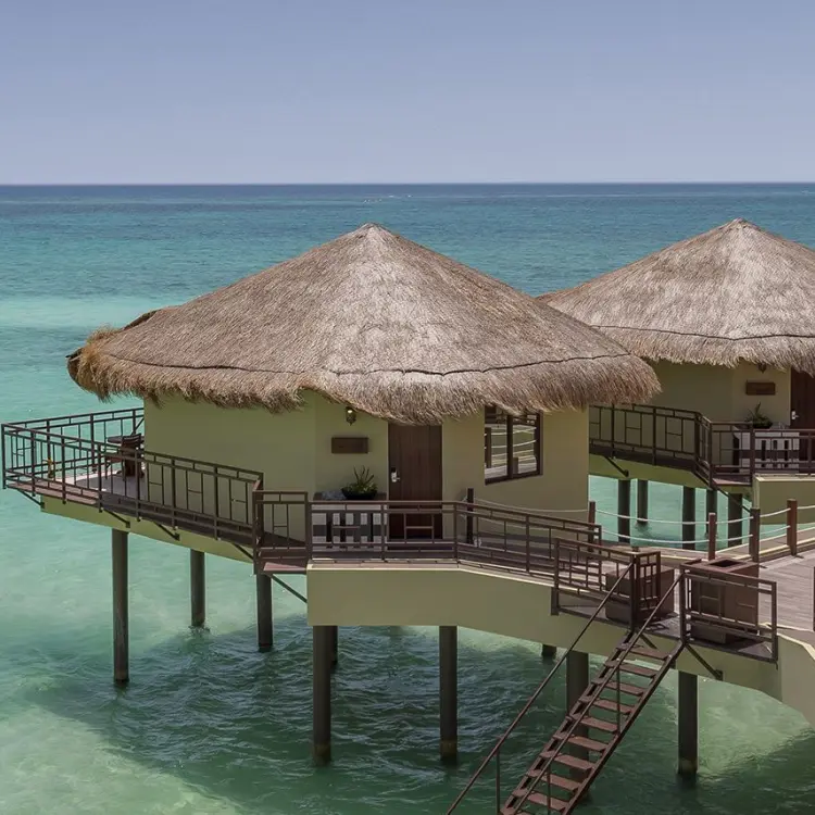 El Dorado Palafitos overwater bungalows with thatched roofs above turquoise water, Riviera Maya