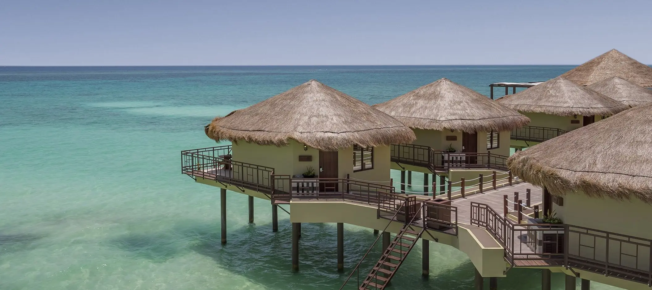 El Dorado Palafitos overwater bungalows with thatched roofs above turquoise water, Riviera Maya