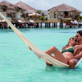 Couple relaxing in an overwater hammock at El Dorado Palafitos, Riviera Maya