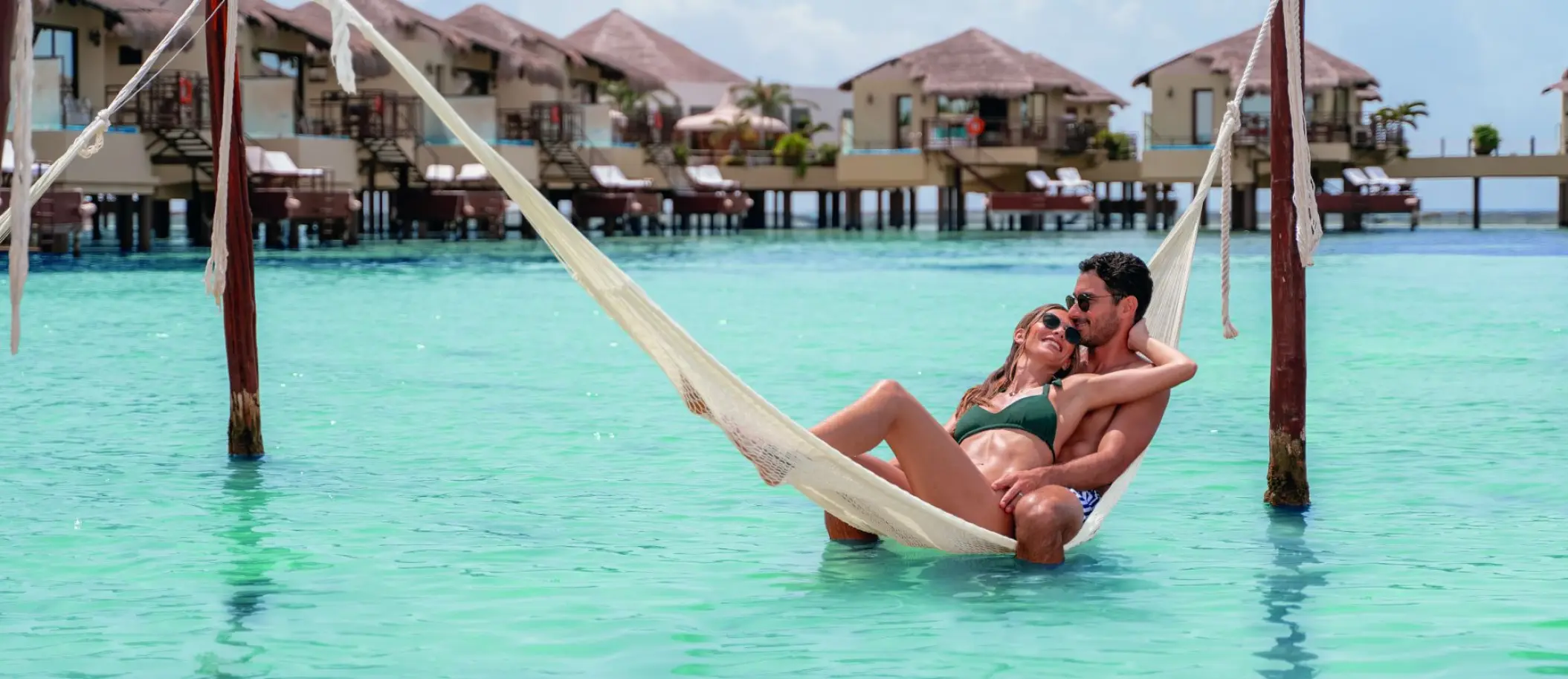 Couple relaxing in an overwater hammock at El Dorado Palafitos, Riviera Maya