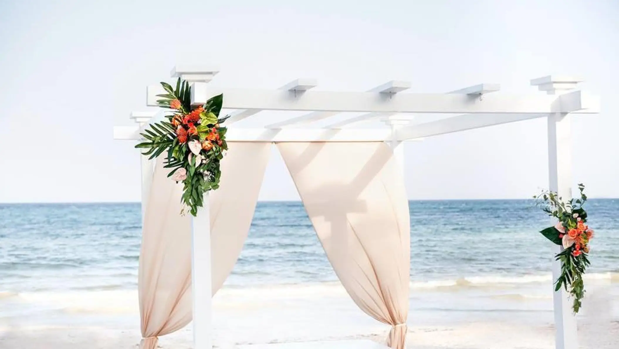 White beach wedding pergola with tropical flowers at Grand Palladium Costa Mujeres, Cancun