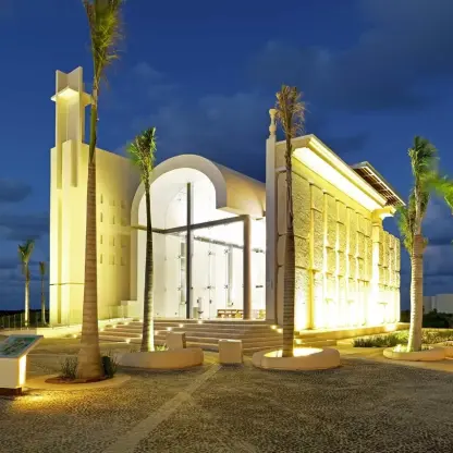 Modern white wedding chapel lit up at night at Grand Palladium Costa Mujeres, Cancun