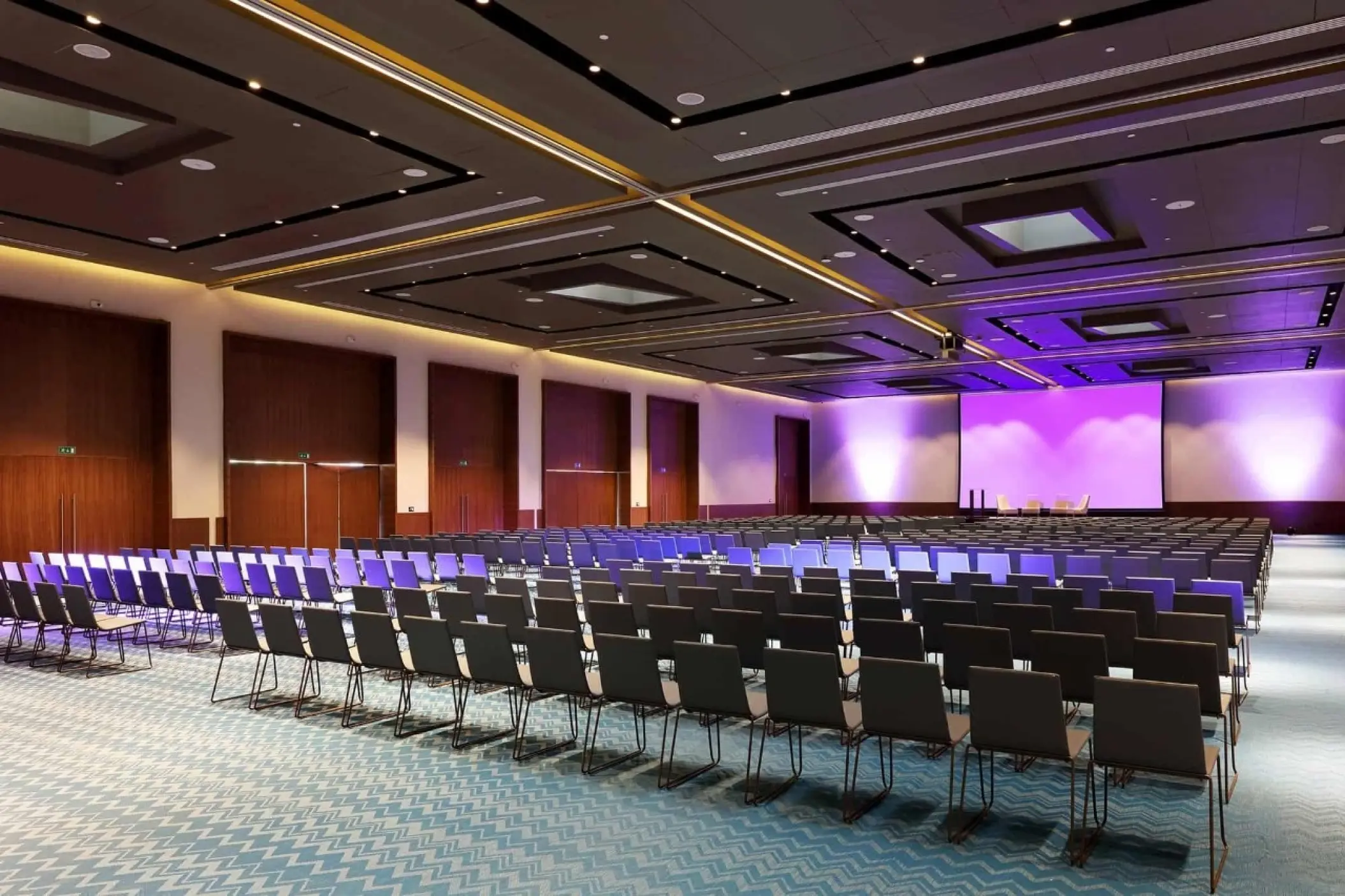 Indoor convention center with rows of seating and a purple-lit stage at Grand Palladium Costa Mujeres, Cancun