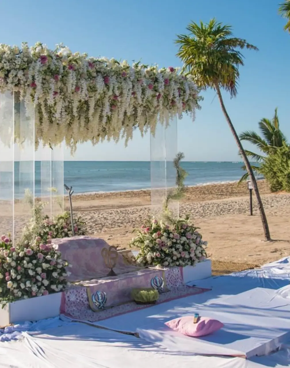 Beachfront wedding ceremony setup with white floral arch at Paradisus Cancun