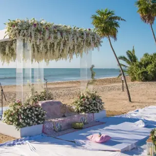 Beachfront wedding ceremony setup with white floral arch at Paradisus Cancun