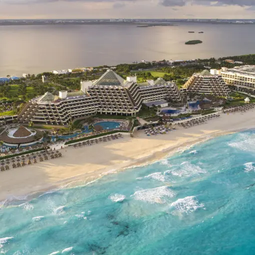 Aerial view of Paradisus Cancun pyramid buildings along the white sand beach and turquoise water, Cancun