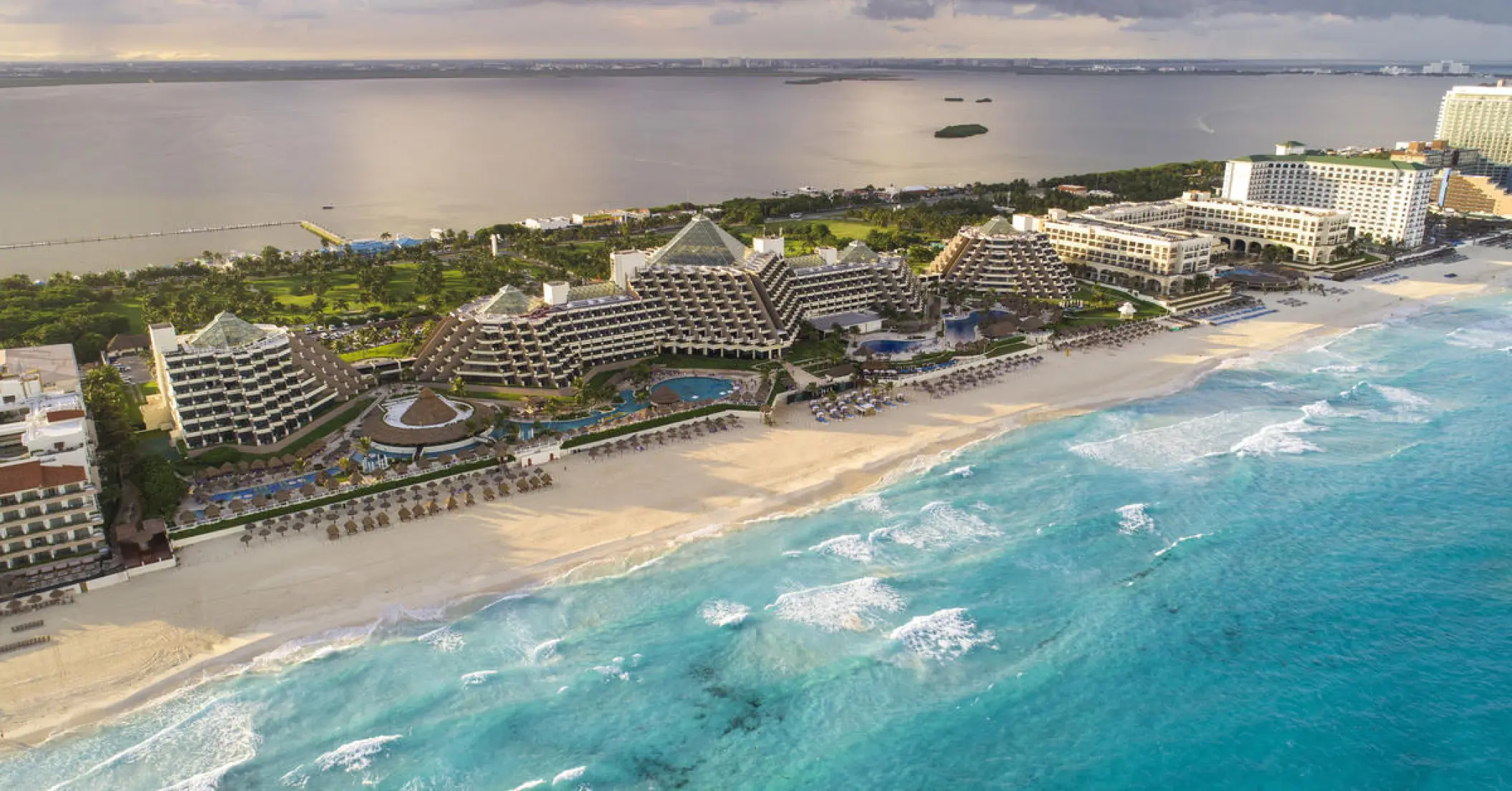 Aerial view of Paradisus Cancun pyramid buildings along the white sand beach and turquoise water, Cancun