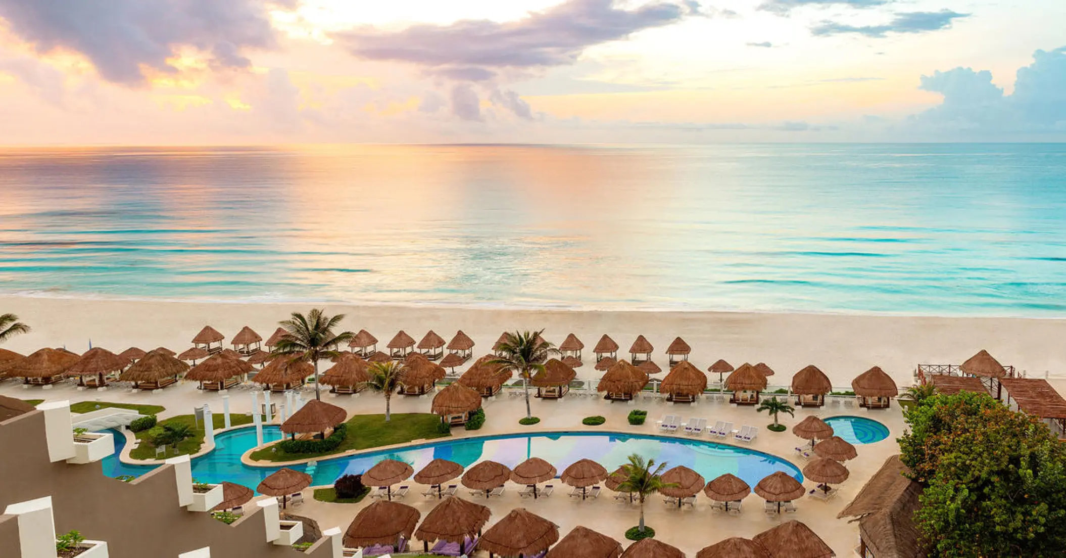 Aerial view of Paradisus Cancun beachfront pool and palapas by the ocean, Cancun