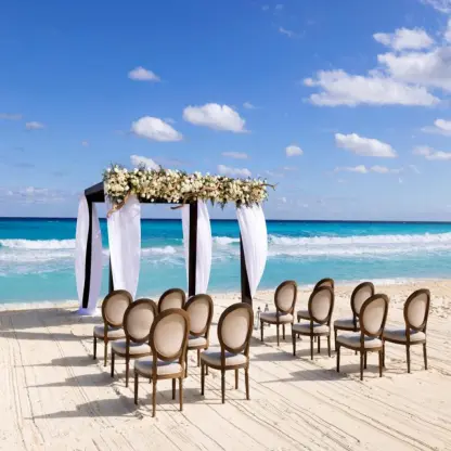 Beachfront wedding ceremony with floral huppah and oval chairs at Paradisus Cancun, Cancun