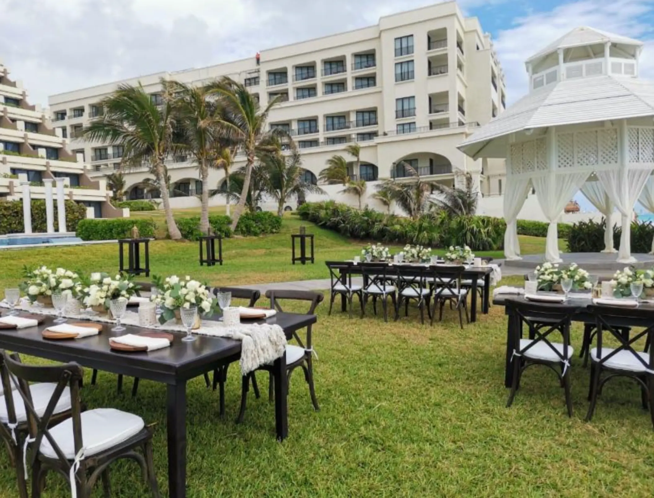 Garden wedding reception with dark wood tables and white gazebo at Paradisus Cancun