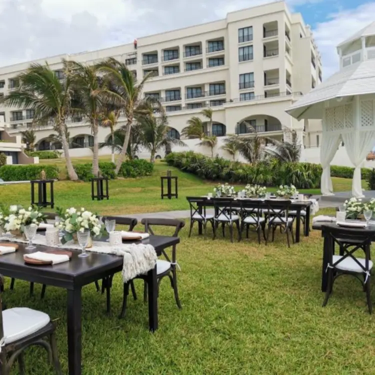 Garden wedding reception with dark wood tables and white gazebo at Paradisus Cancun