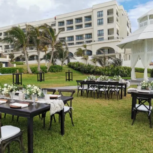 Garden wedding reception with dark wood tables and white gazebo at Paradisus Cancun