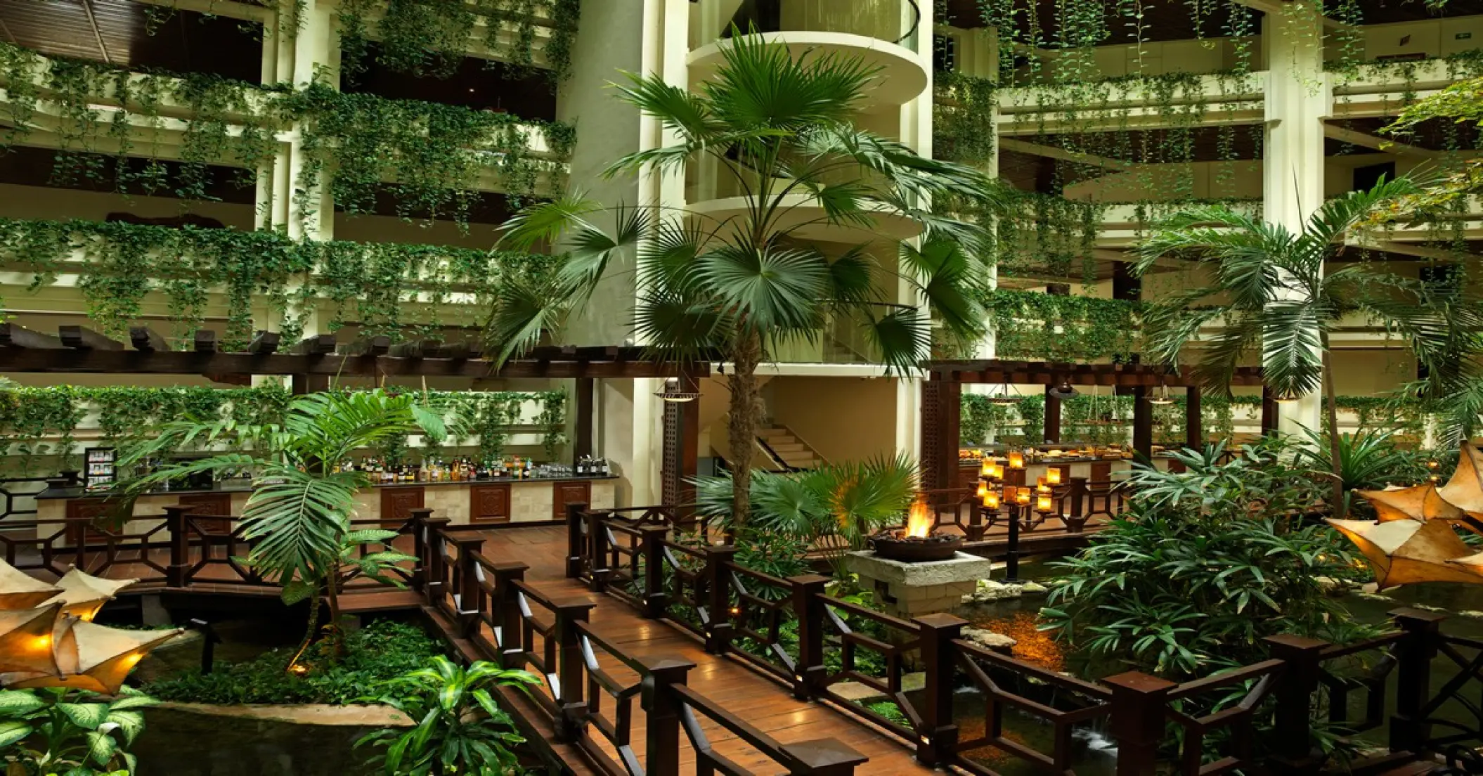 Indoor garden atrium with wooden walkways and hanging vines at Paradisus Cancun