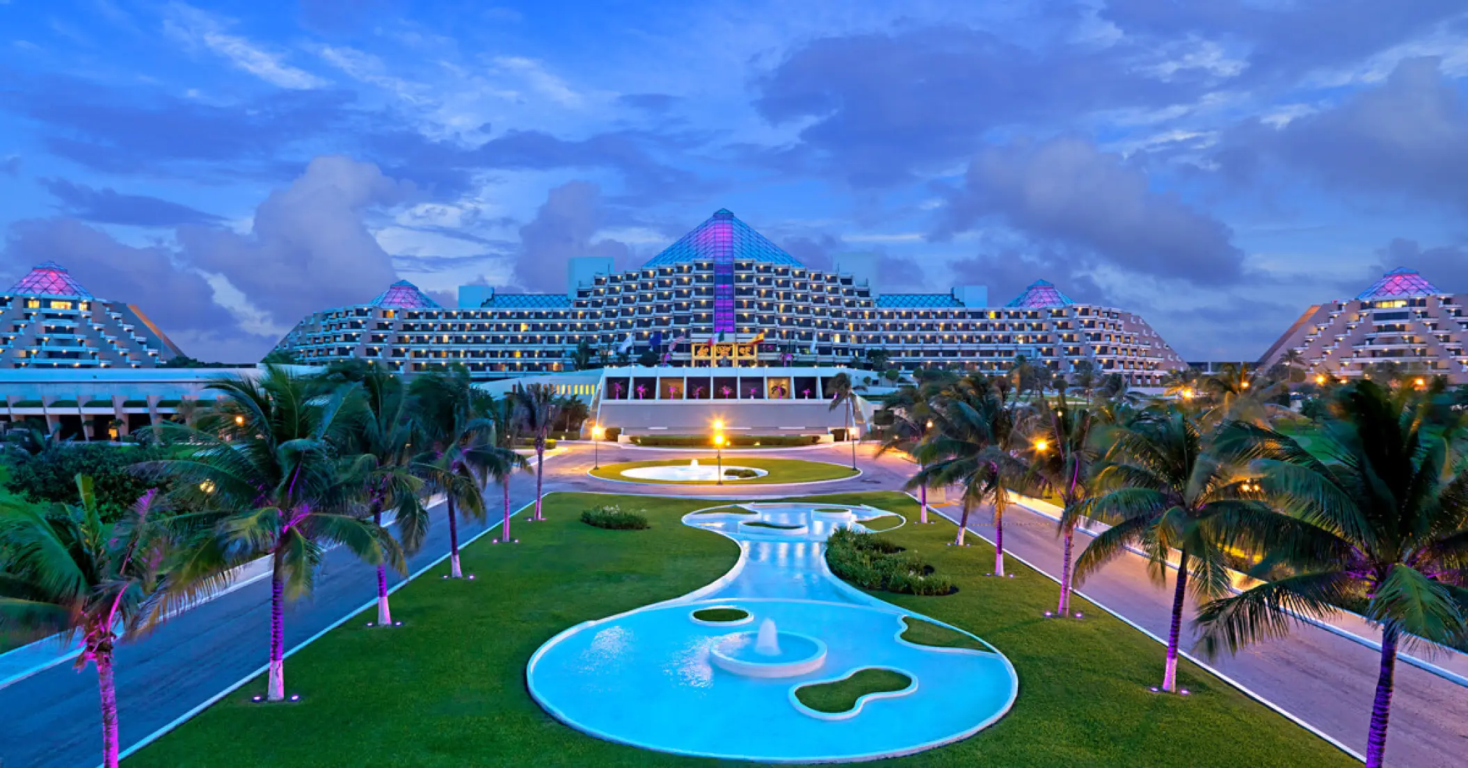 Paradisus Cancun pyramid-style buildings and illuminated pool area at dusk, Cancun