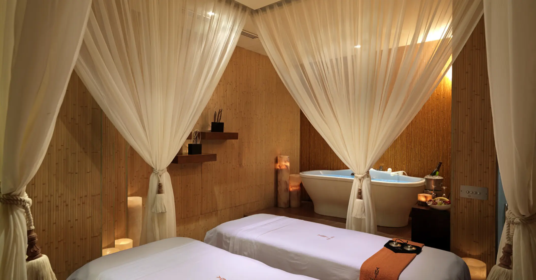 Couples massage suite with white curtains and a soaking tub at Paradisus Cancun
