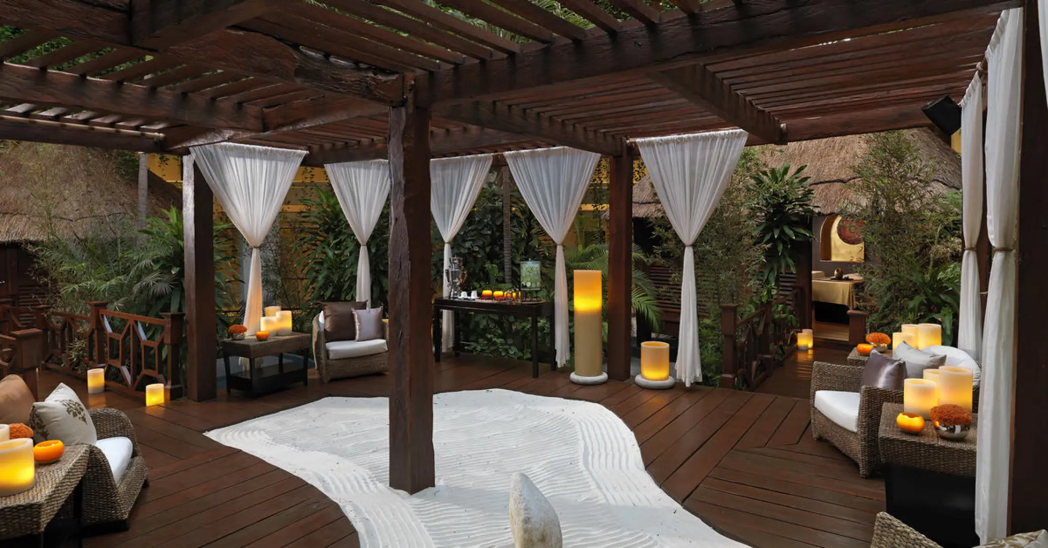 Outdoor spa lounge with wooden pergola and white curtains at Paradisus Cancun, Cancun
