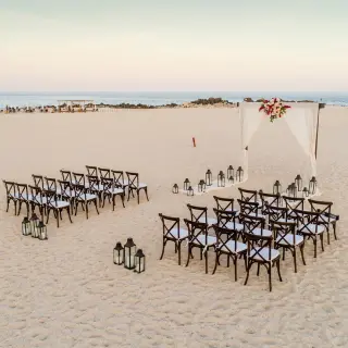 Beachfront wedding ceremony with wooden cross-back chairs at Paradisus Los Cabos, Cabo San Lucas