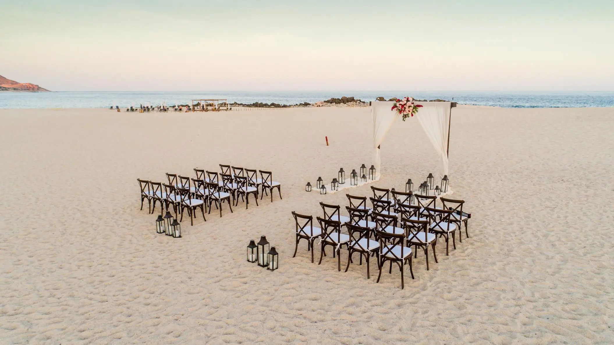 Beachfront wedding ceremony with wooden cross-back chairs at Paradisus Los Cabos, Cabo San Lucas