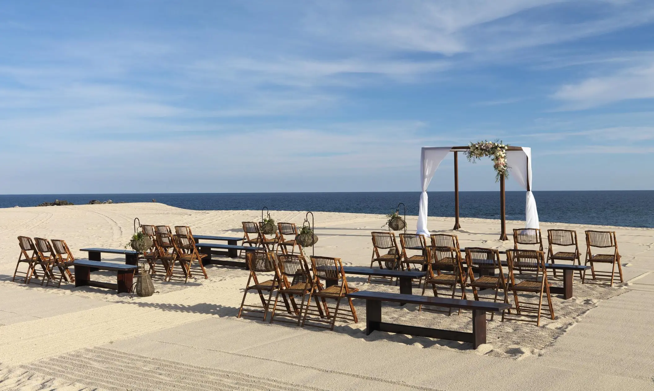 Beachfront wedding ceremony with wooden benches and white gazebo at Paradisus Los Cabos, Cabo San Lucas