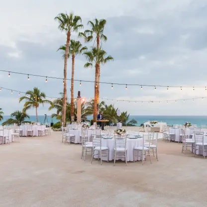 Ocean terrace wedding reception with string lights and white tables at Paradisus Los Cabos, Cabo San Lucas