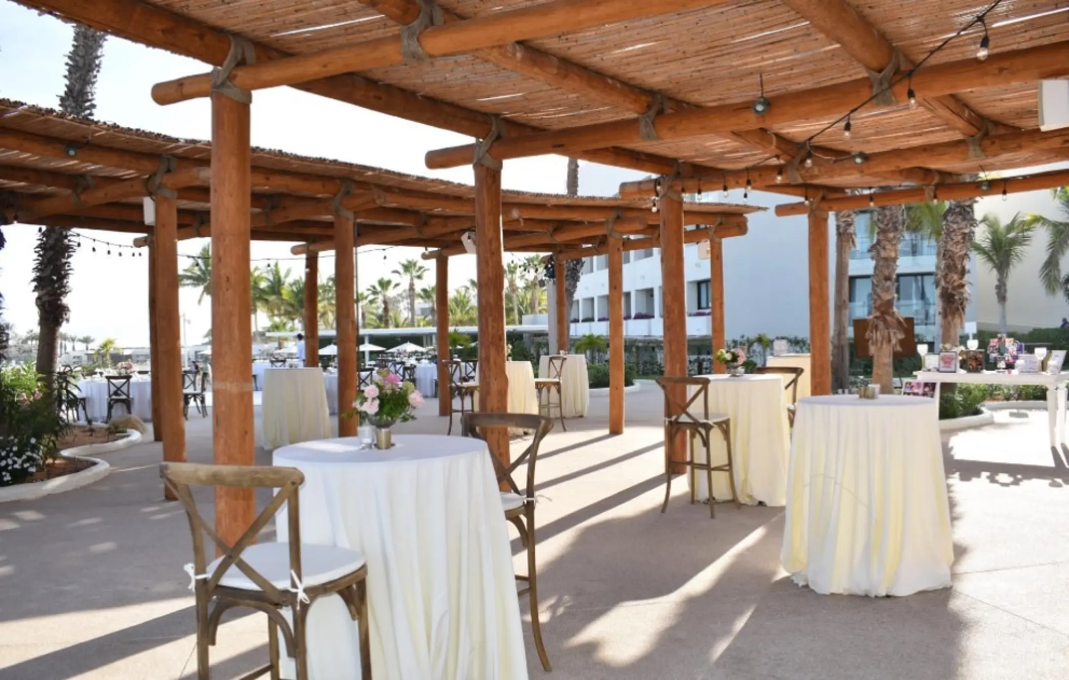 Outdoor wedding reception setup under a rustic wooden pergola at Paradisus Los Cabos, Cabo San Lucas