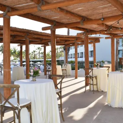 Outdoor wedding reception setup under a rustic wooden pergola at Paradisus Los Cabos, Cabo San Lucas