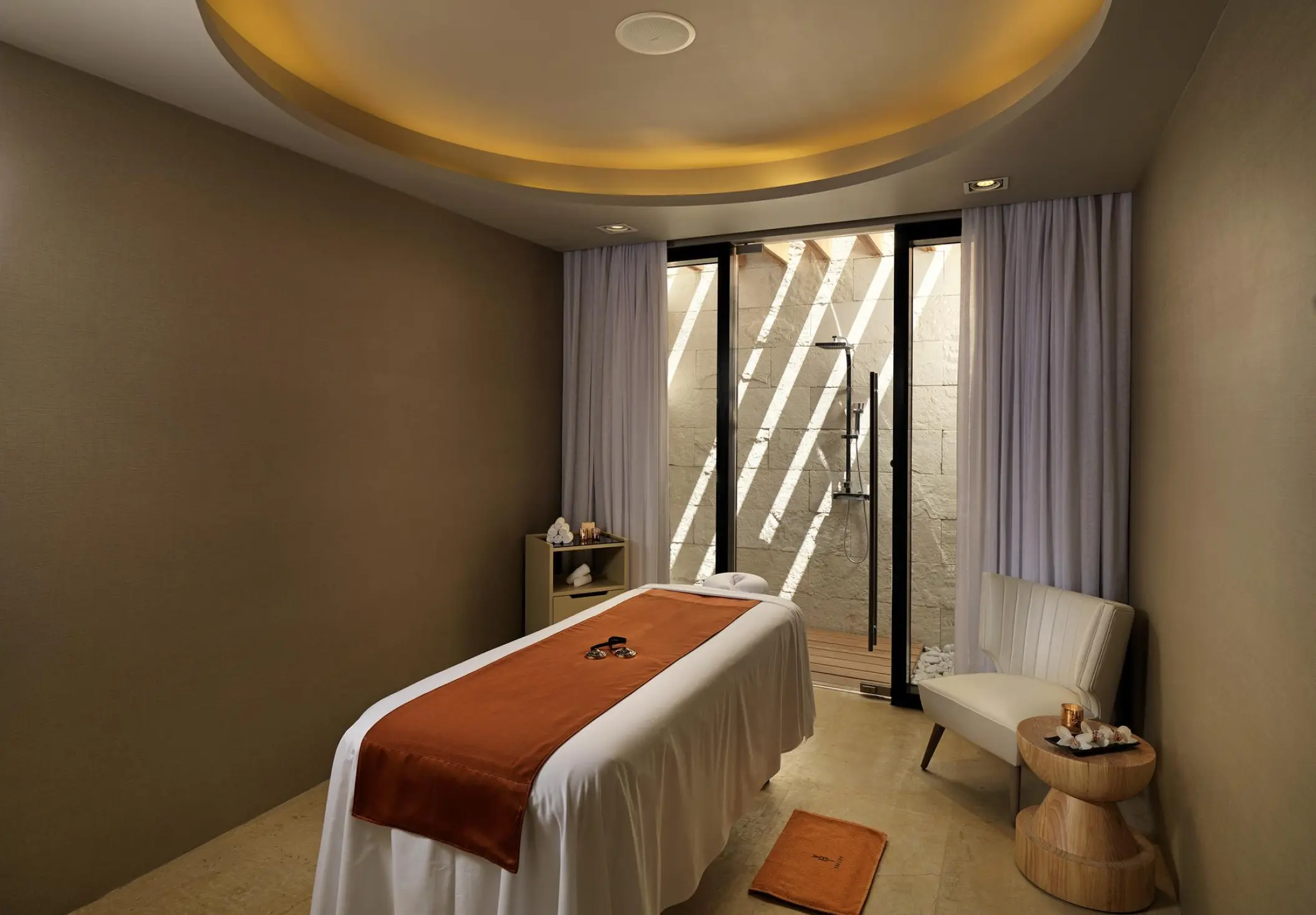 Spa treatment room with a massage bed and outdoor shower at Paradisus Los Cabos, Cabo San Lucas