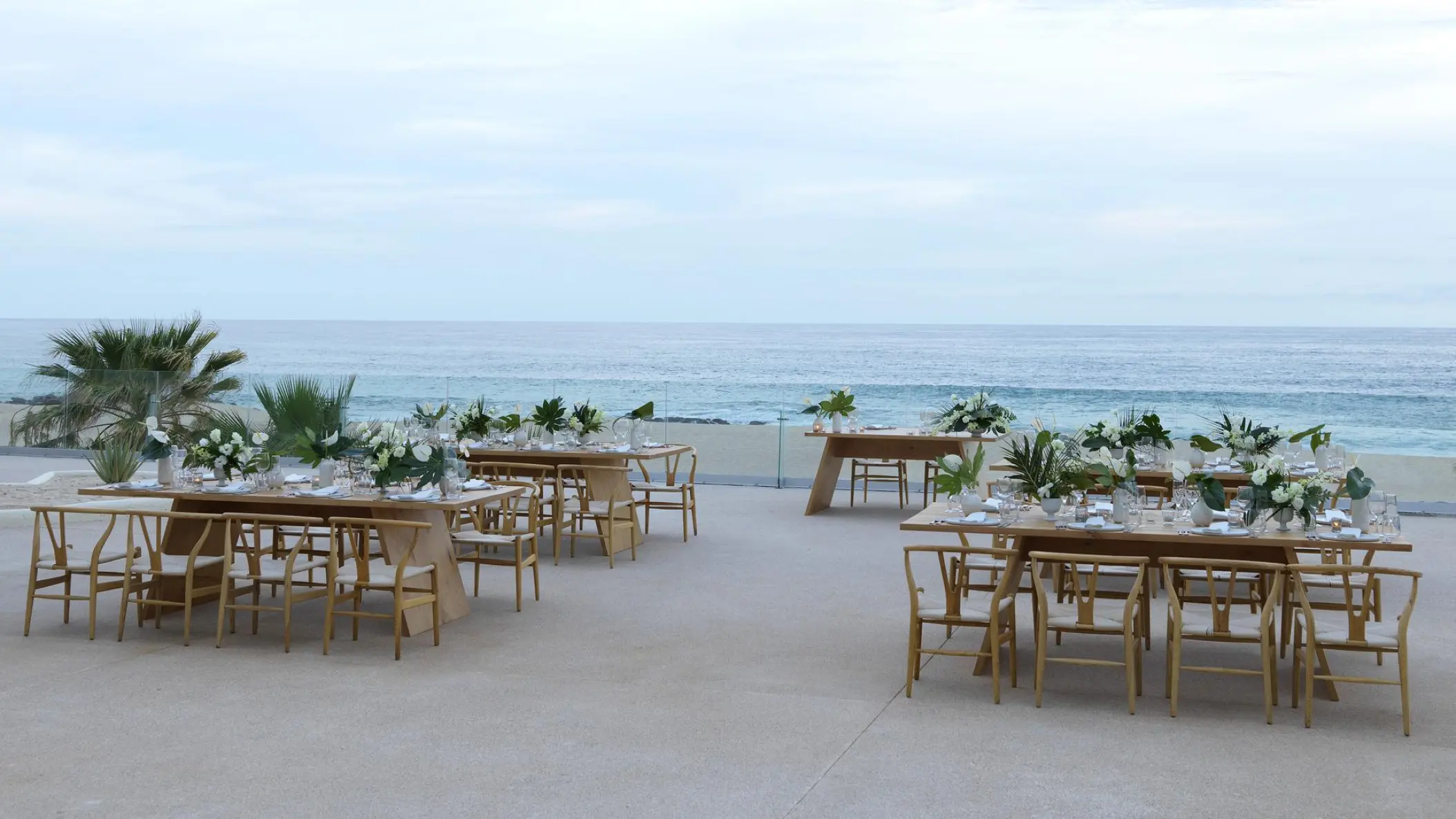 Outdoor wedding reception with wooden tables and white floral centerpieces at Paradisus Los Cabos, Cabo San Lucas
