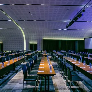 Convention center reception hall with rows of tables and a stage at Paradisus La Perla, Playa Del Carmen
