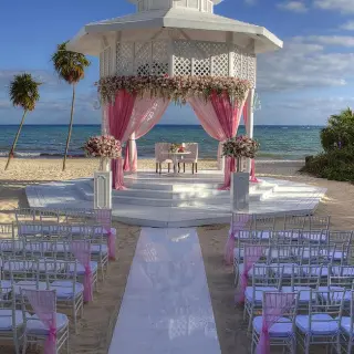 Beachfront wedding ceremony with a white gazebo and pink drapes at Paradisus Playa Del Carmen